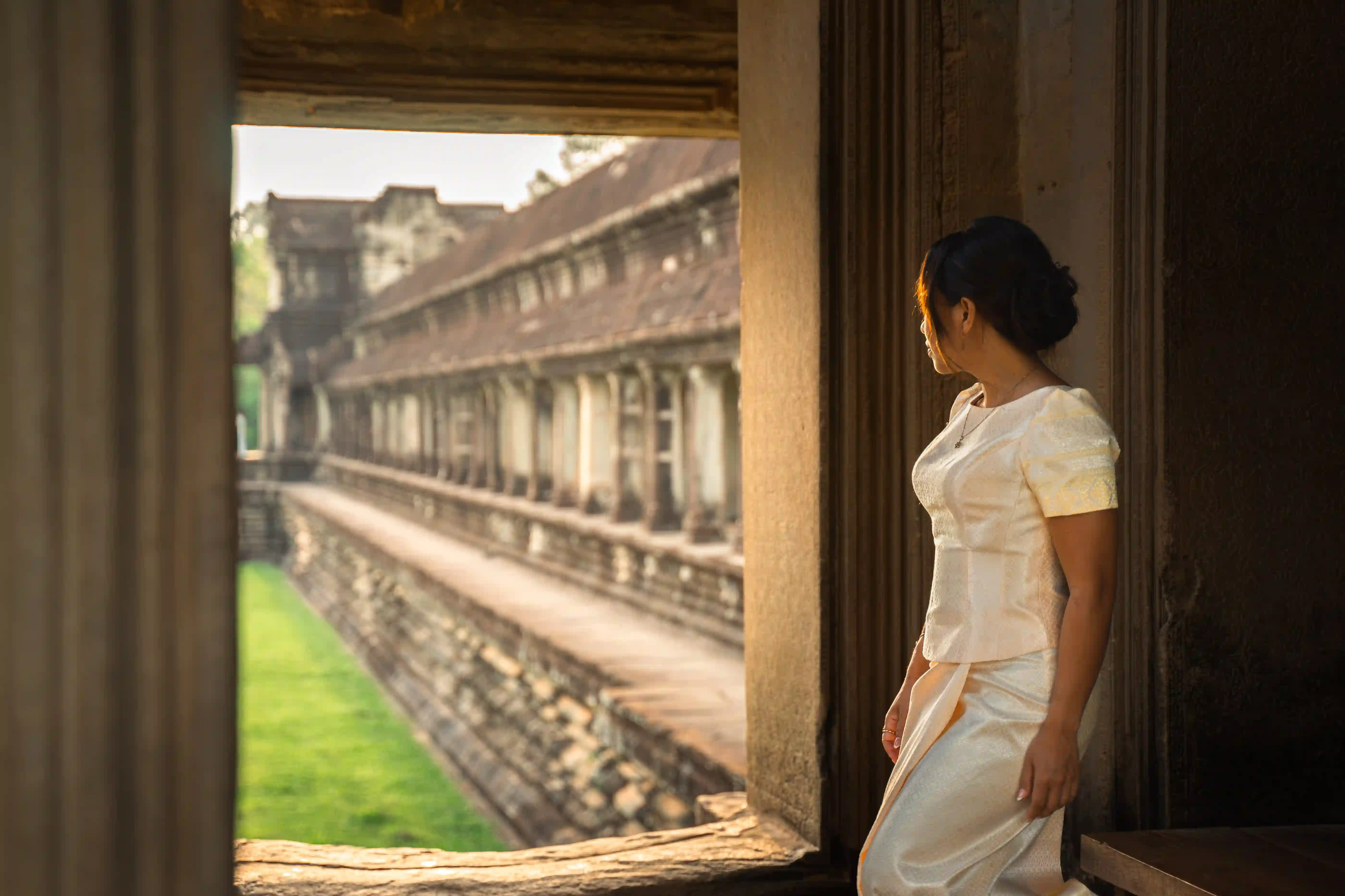 Ancient temples in Cambodia at sunrise with mist-covered horizon and palm tree silhouettes